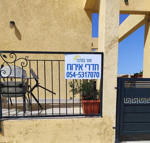 a sign on a balcony with a table and a chair at זוהר במדבר ים המלח in Neve Zohar
