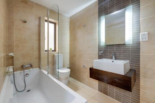 a bathroom with a tub and a sink and a toilet at Sliema Tigne Suites in Sliema