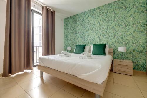 a bedroom with a large bed with green wallpaper at Sliema Tigne Suites in Sliema