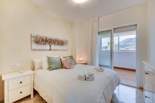 een slaapkamer met een wit bed en een raam bij VB Golf Beach 2BDR Apt in Benalmádena