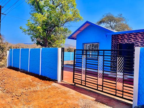 a blue house with a gate and a fence at Blue House Karjat Cottage in Chinchavli