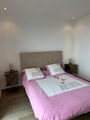 - un lit avec des draps et des oreillers roses et blancs dans l'établissement Appartement Cardo, à Bastia