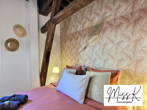 um quarto com uma cama e uma parede com um mural de penas em ''La Fenêtre sur le marché'' de Miss.K Conciergerie em Châtillon-sur-Chalaronne
