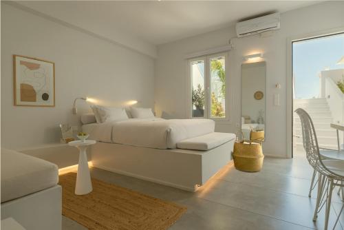 a white bedroom with a bed and a living room at AELIA Tinos in Tinos