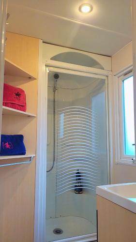une douche avec une porte vitrée dans une salle de bain dans l'établissement Camping Marvilla Parks -Parc des roches 91530, à Saint-Chéron