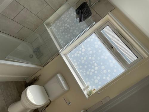 a bathroom with a toilet and a large window at Super Convenient 2 Double Bed apartment for Central London - 30 seconds walk to platform train station and 19 mins to London Waterloo in London