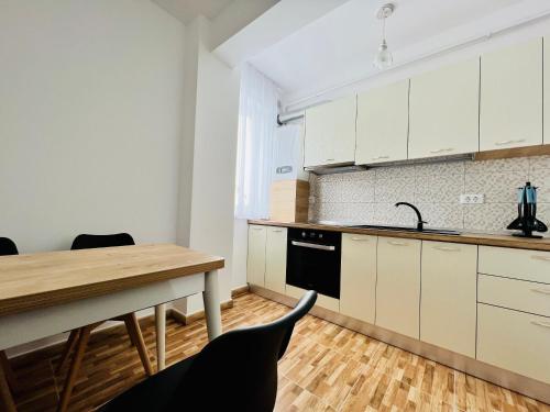 uma cozinha com armários brancos e uma mesa de madeira em Altheda Living Brownie 29E-2 em Suceava