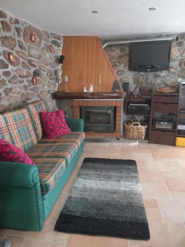 a living room with a couch and a stone fireplace at Caramulo - Abrigo Serrano in Carvalhal da Mulher
