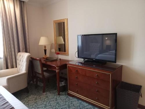 a hotel room with a television on a dresser with a chair at Elite Park Hotel in Jeddah