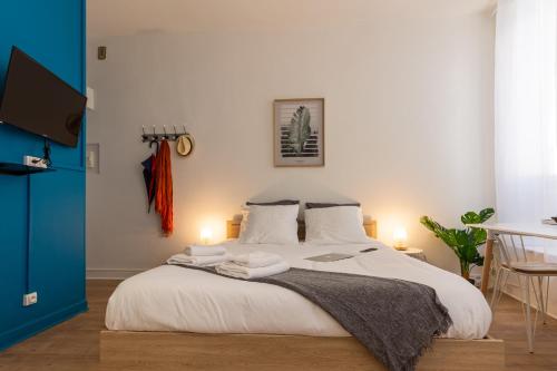 VilleneuveCityStay - Tropical & Studio Chic في فيلنوف-سور-لو: غرفة نوم عليها سرير وفوط