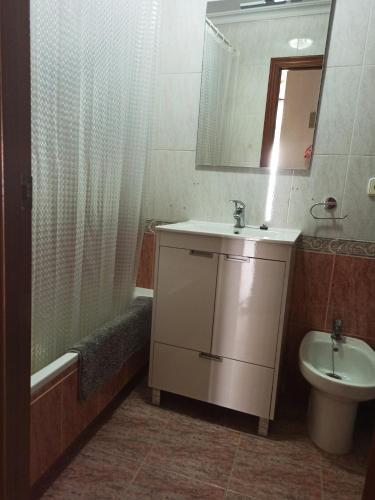 a bathroom with a sink and a toilet and a mirror at El Rincón de Umbria in Punta Umbría