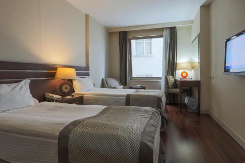 a hotel room with two beds and a flat screen tv at Niza Park Hotel in Ankara