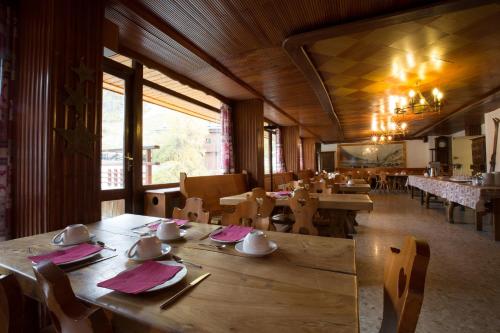 un restaurante con mesas y sillas de madera y una gran ventana en Les Crêtes Blanches en Val dʼIsère
