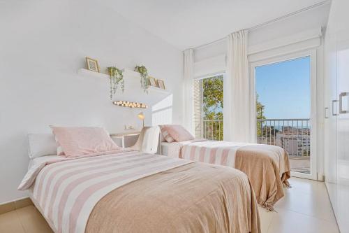 2 łóżka w białym pokoju z oknem w obiekcie Stylish apartment with oceanview w Maladze