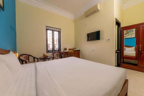 a bedroom with a large white bed and a television at Hoi An Heart hostel Villa - Bespoke in Hoi An