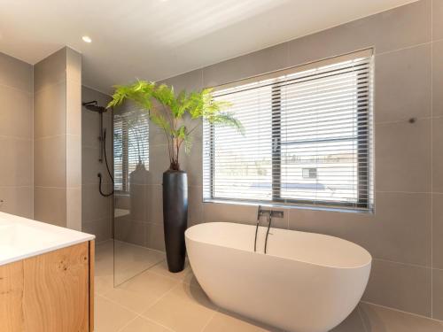 een badkamer met een wit bad en een plant in een raam bij Modern water villa in Zeewolde with jetty in Zeewolde