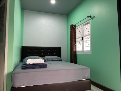um quarto com uma cama com paredes verdes e uma janela em ดอยตุง สันติสุขโฮมสเตย์ em Ban Pa Kluai La Hu