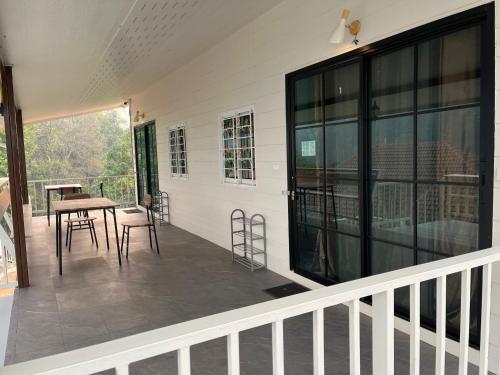 un porche cubierto con mesa y sillas en ดอยตุง สันติสุขโฮมสเตย์, en Ban Pa Kluai La Hu
