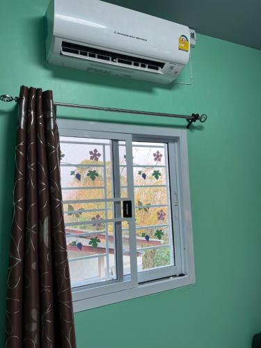 a window with a air conditioner next to a window at ดอยตุง สันติสุขโฮมสเตย์ in Ban Pa Kluai La Hu