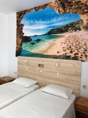 a bedroom with two beds and a painting of a beach at Antonis Hotel in Kefalos