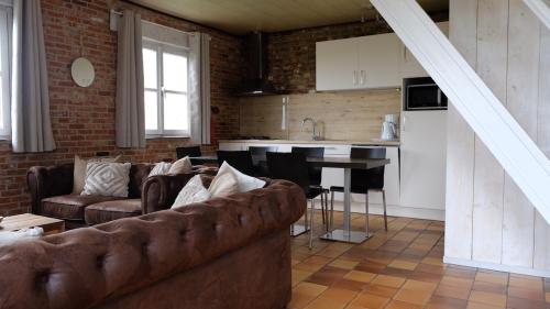 ein Wohnzimmer mit einem Sofa und einer Küche in der Unterkunft De Vitsemolenhoeve in Westouter