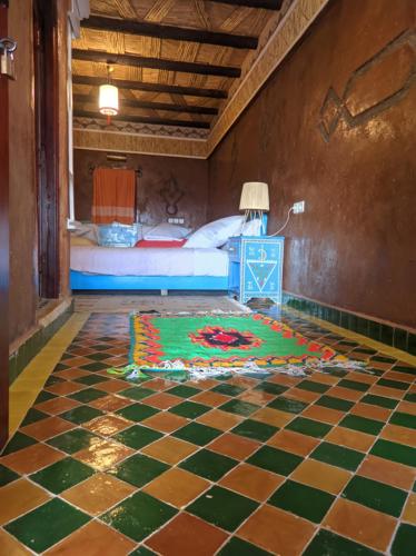 a bedroom with a bed and a checkerboard floor at Kasbah Assafar in Kalaat MGouna