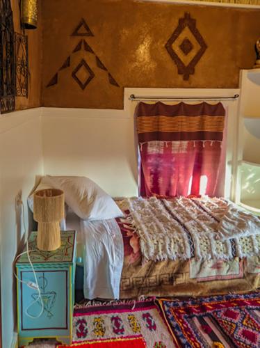 a bedroom with a bed and a table with a rug at Kasbah Assafar in Kalaat MGouna