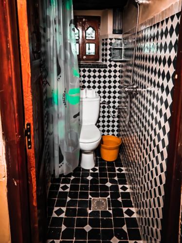 a bathroom with a toilet and black and white tiles at Kasbah Assafar in Kalaat MGouna
