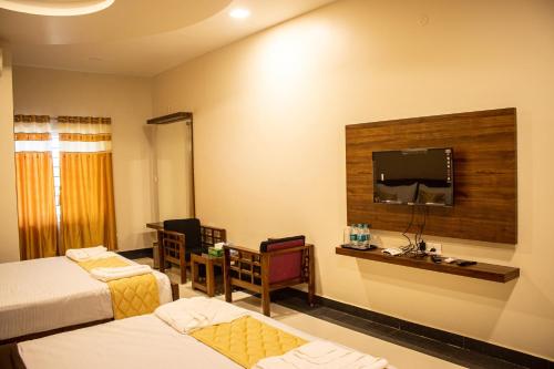 Habitación de hotel con 2 camas y TV de pantalla plana. en Faiz Residency en Rāmanāthapuram