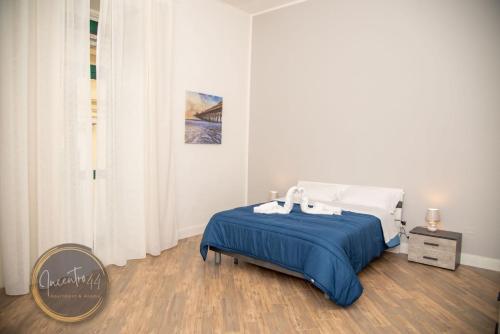 a white bedroom with a bed with a blue blanket at Incentro 44 in Cava deʼ Tirreni