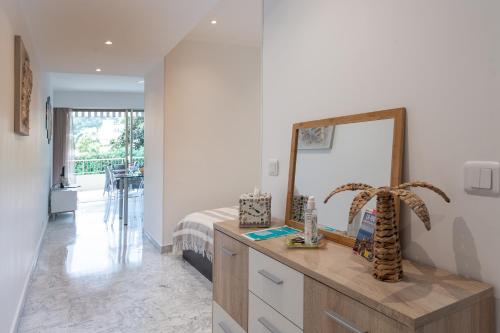 een slaapkamer met een dressoir met een spiegel en een bed bij Studio Menton Garavan avec piscine à proximité Italie et Monaco in Menton