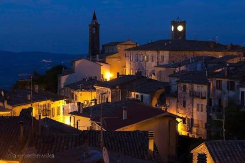 eine nachts beleuchtete Stadt mit einem Uhrturm in der Unterkunft Zara House in CastellʼAzzara