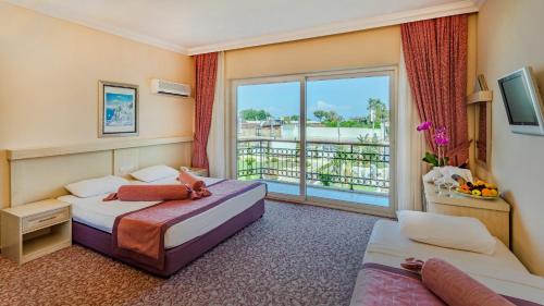 a hotel room with two beds and a balcony at Club Hotel Belpınar in Beldibi