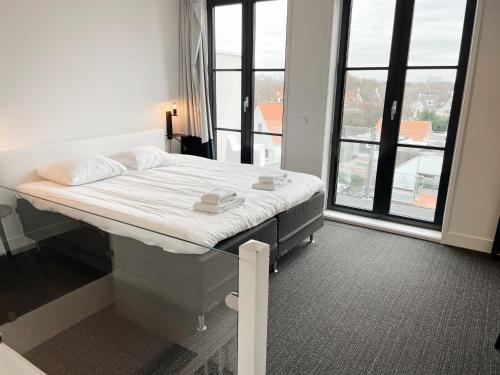 un lit d'hôpital dans une chambre avec une grande fenêtre dans l'établissement Hello Zeeland - Appartement Markt 4 en 4A, à Domburg