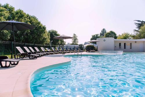 une piscine avec chaises longues et parasols dans l'établissement Villages Clubs du Soleil - BEG MEIL, à Fouesnant