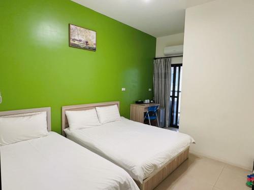 two beds in a room with a green wall at 時光旅舍 in Jincheng