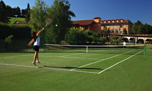 a woman hitting a tennis ball on a tennis court at Relais Sant'Uffizio Wellness & Spa in Cioccaro