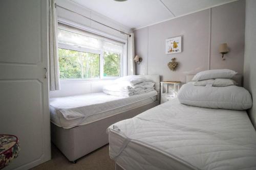 two beds in a small room with a window at Pet Friendly, Luxury Lodge With Decking In Suffolk Near The Beach Ref 32108a in Lowestoft