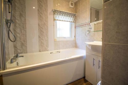 a bathroom with a bath tub and a sink at Pet Friendly, Luxury Lodge With Decking In Suffolk Near The Beach Ref 32108a in Lowestoft