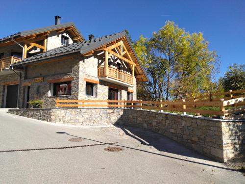 a house with a stone retaining wall and a fence at Chalet des Lys - tout confort - 12 personnes in Valloire