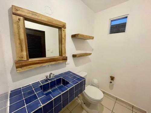 a bathroom with a toilet with a mirror and blue tiles at MIO Tulum Hotel Boutique in Tulum