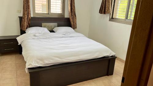 a large bed with white sheets and pillows at Villa in village in Dāliyat el Karmil