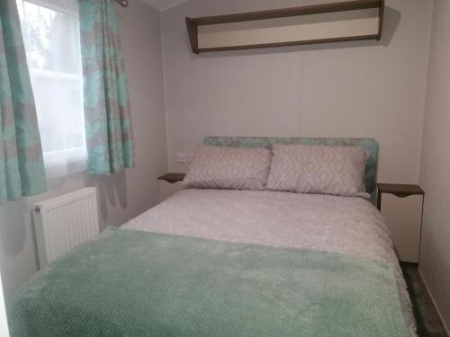 a small bedroom with a bed with a green blanket at Beautiful 8 Berth Caravan At Wild Duck Haven Park In Norfolk Ref 11195sc in Great Yarmouth