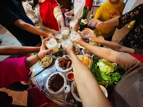 een groep mensen die rond een tafel zitten met drankjes bij Căn Hộ Nghĩ Dưỡng Tuấn Hải - Nhà Chị Hai in Bao Loc