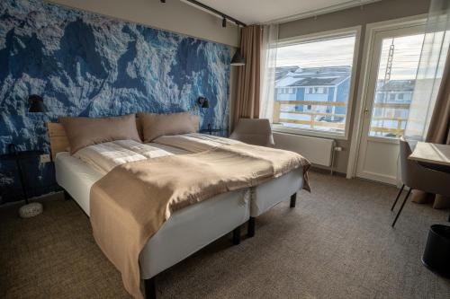 a bedroom with a bed with a blue wall at Hotel Hvide Falk in Ilulissat