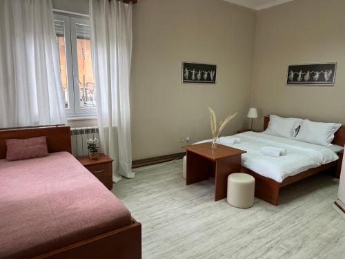 ein Hotelzimmer mit 2 Betten und einem Tisch in der Unterkunft Garden Vila in Vrnjačka Banja