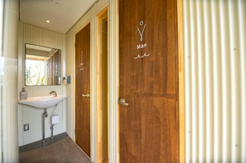 a bathroom with a sink and a wooden door at てんとうみ 渋川海岸グランピング Tentoumi Shibukawa Beach Glamping in Tamano