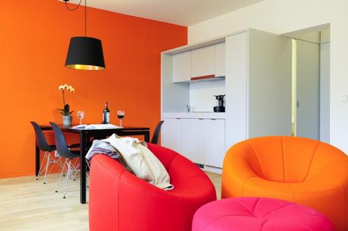 - un salon avec des chaises orange et une table dans l'établissement Key Inn Appart Hotel Parc de Merl, à Luxembourg