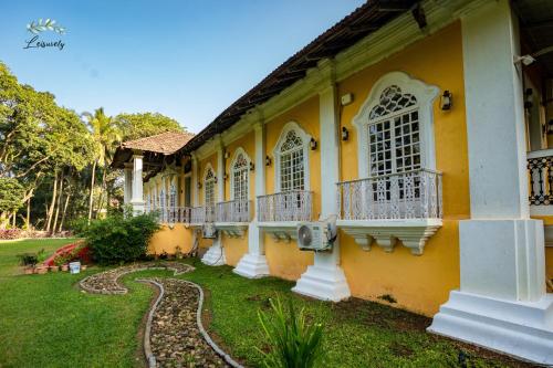 a yellow building with balconies and a yard at Silva Heritage Resort Goa in Benaulim