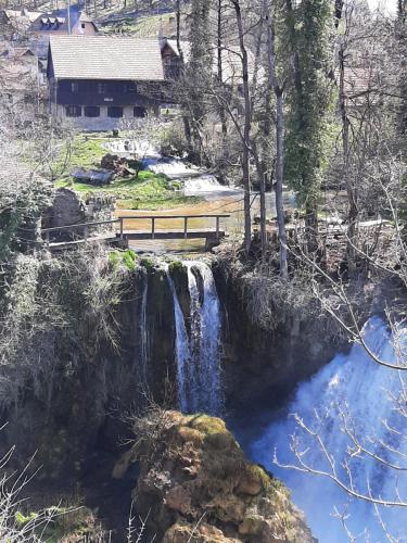 un banco sentado en la parte superior de una cascada junto a un río en Sobe Ivan Rastoke 21, en Slunj